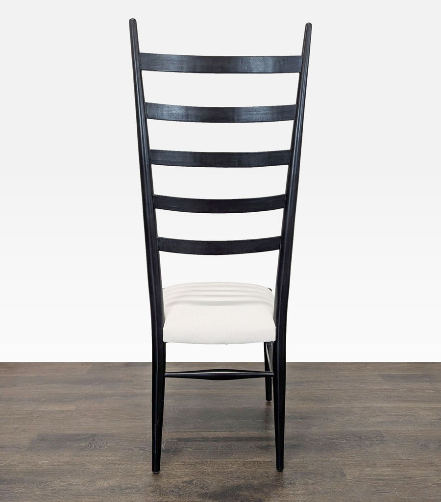 Rear view of modern black chair, highlighting the high ladder-back design and soft white cushion.