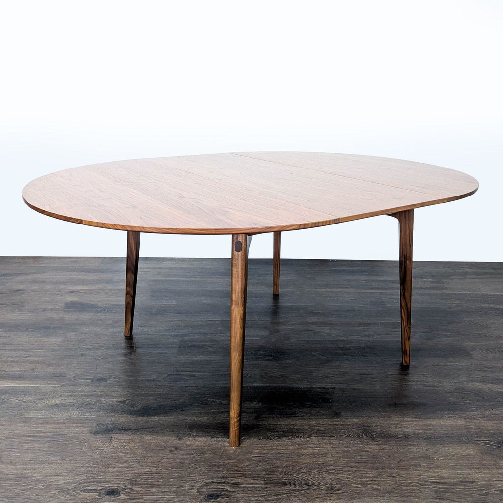 Modern walnut dining table by Matthew Hilton with extendable top, distinctive angled legs, and artisanal detailing.