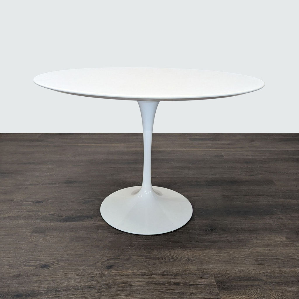A sleek white Knoll chair and table from Eero Saarinen’s Pedestal Collection featuring single central bases.