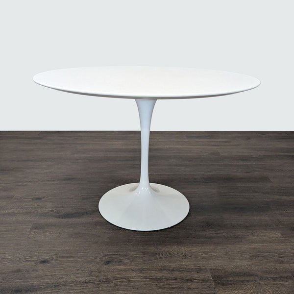 Minimalist round Knoll dining table with single pedestal base, designed by Eero Saarinen for a clean modern look.