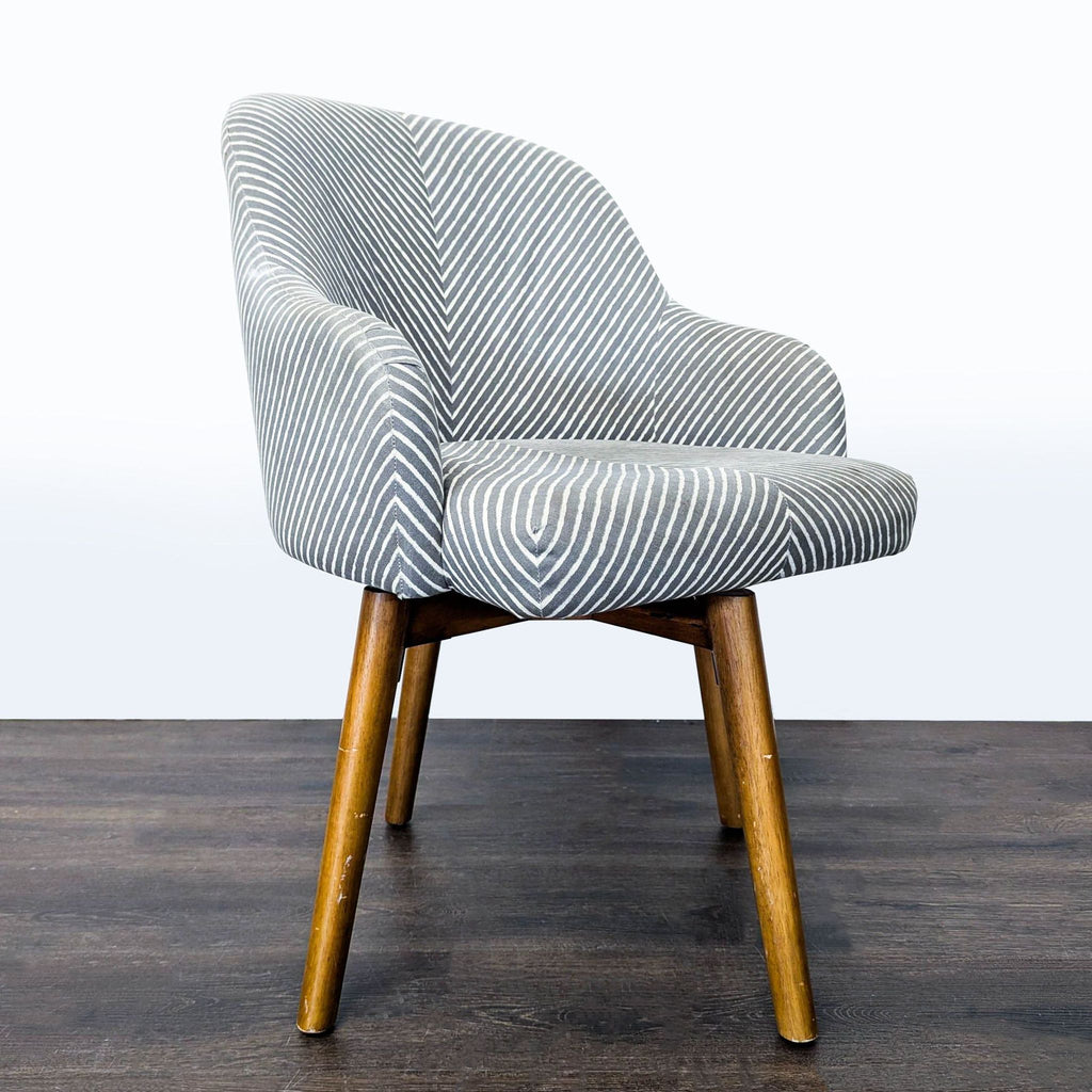 Contemporary lounge chair with striped upholstery, curved design, and sturdy wood swivel base from West Elm.