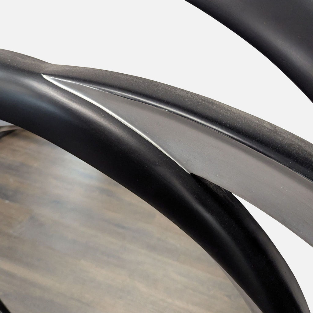 Contemporary Coaster mirror with bold interlinked loops in shiny black and silver accents.