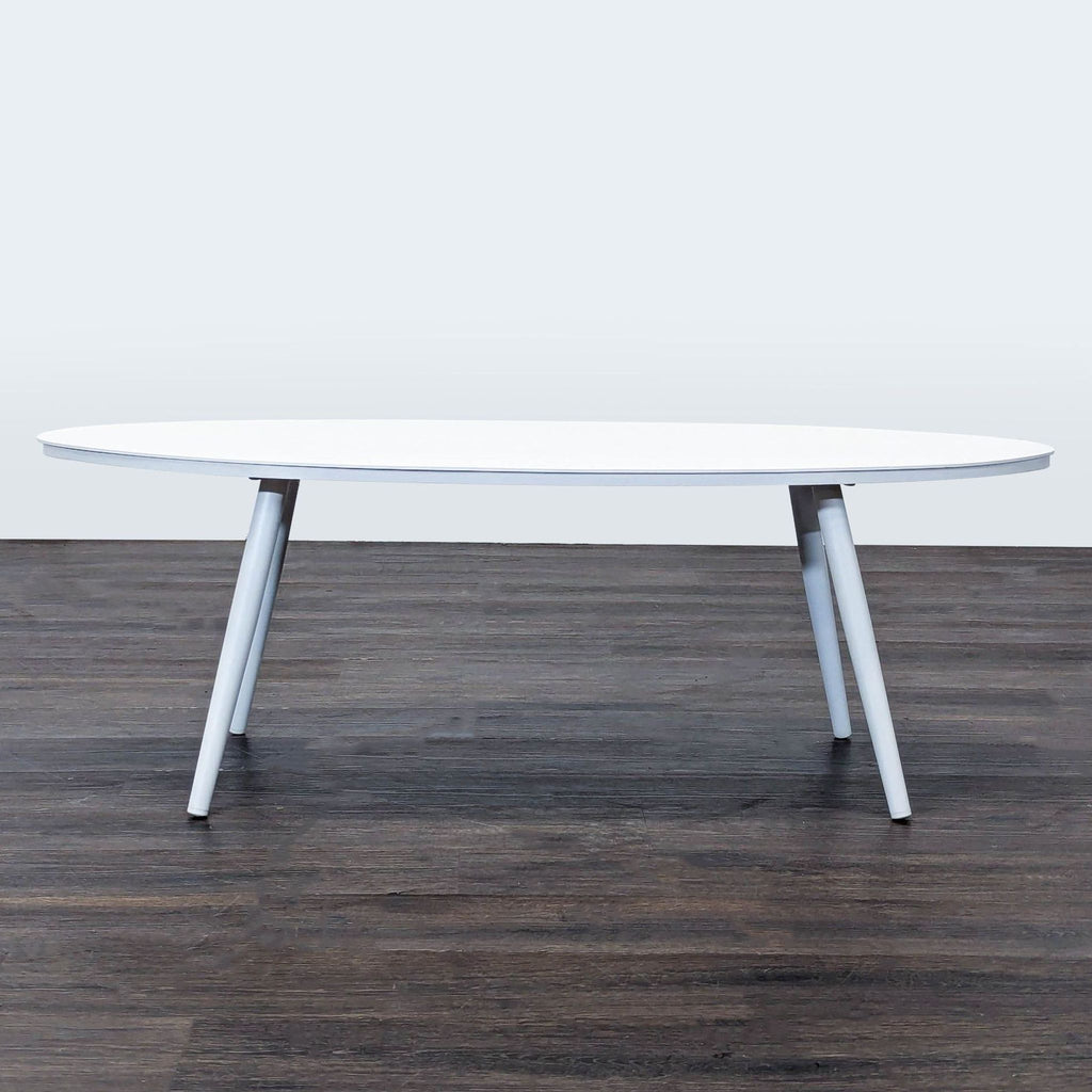 Sleek white oval coffee table by Article with angled legs, offering a modern and minimalist design.