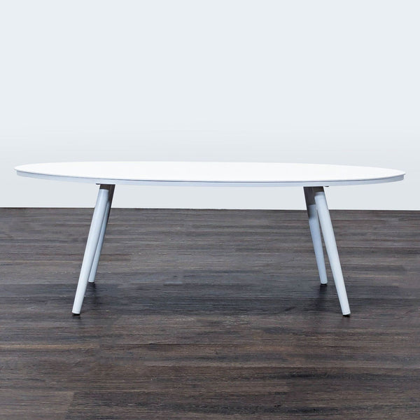 Sleek white oval coffee table by Article with angled legs, offering a modern and minimalist design.