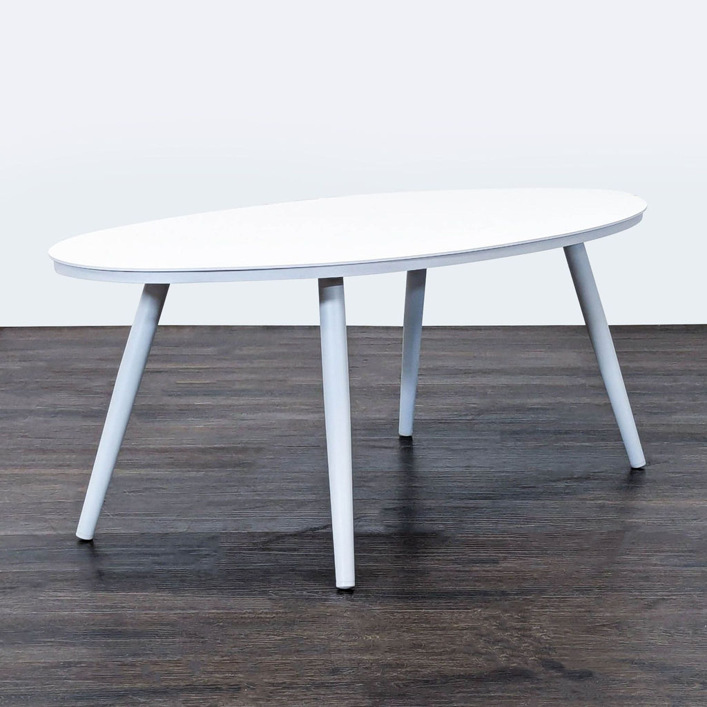 Article brand white oval table, designed with angled legs, ideal for stylish and functional living spaces.