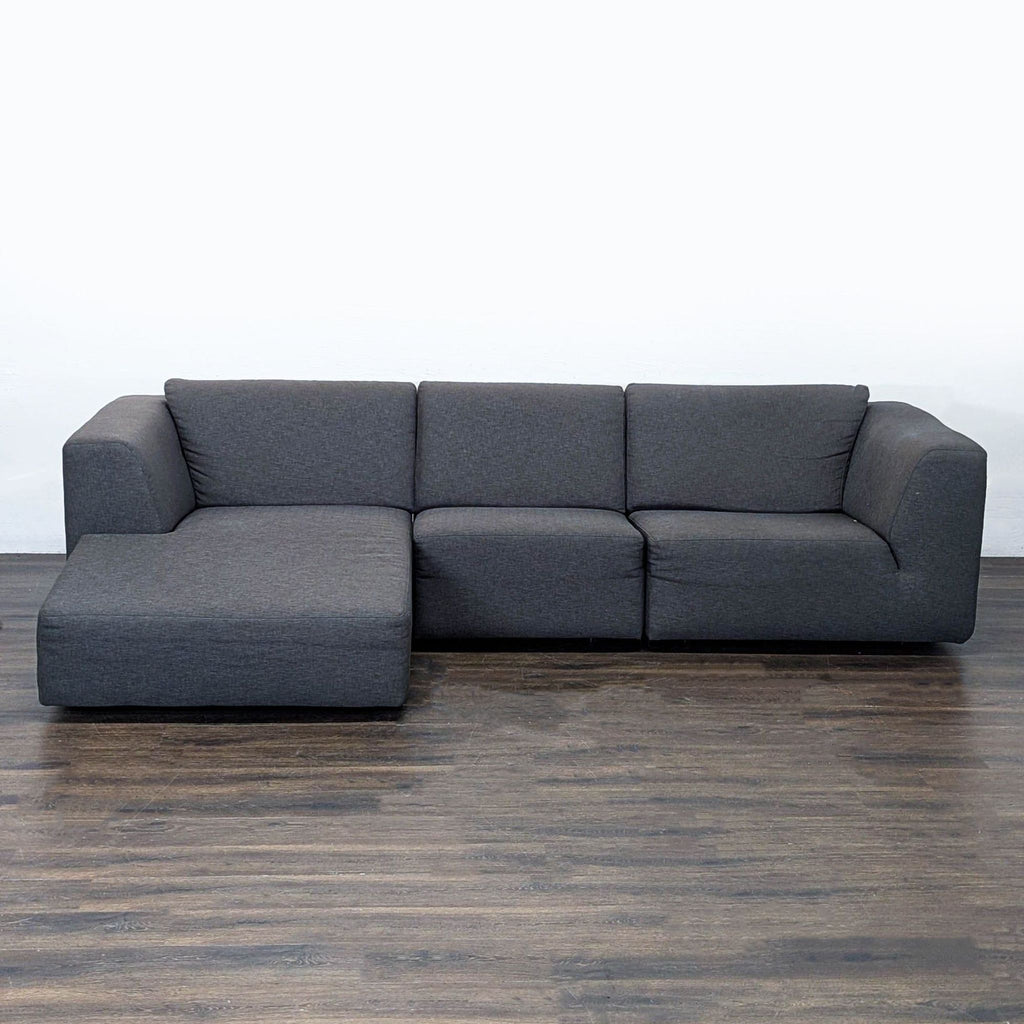 1. Modern dark grey EQ3 sectional sofa with left-facing chaise, pictured on a wood floor, front view.  