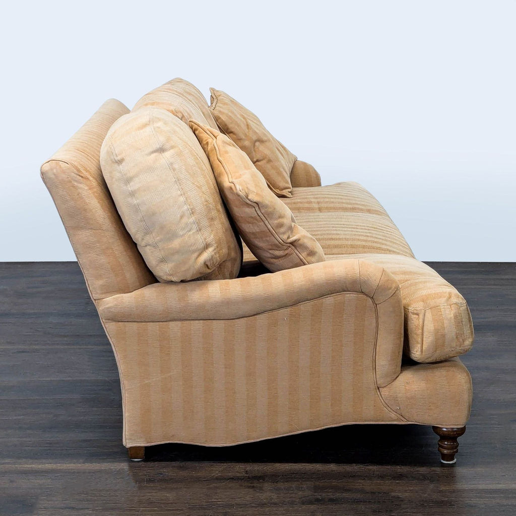 Three-seat sofa from Crate & Barrel, upholstered in beige stripes with matching pillows and durable wood legs.