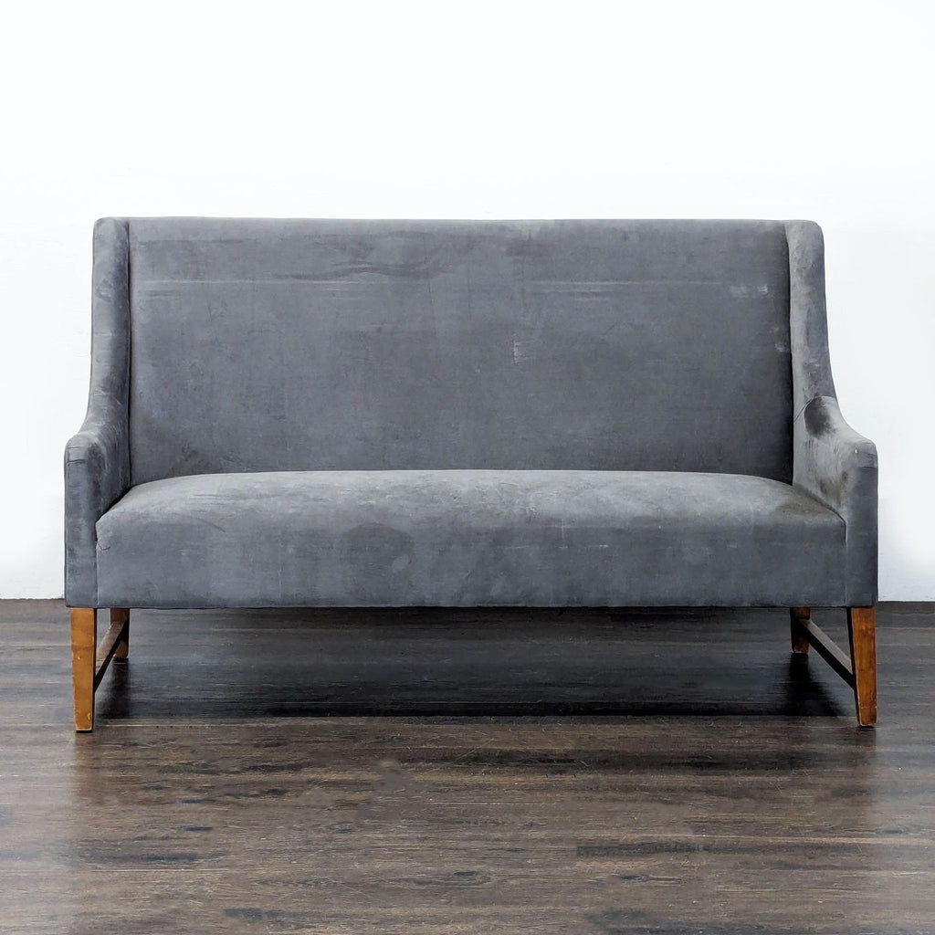 Modern grey Pier One loveseat with soft upholstery, sturdy wooden legs, and a minimalist design, seats two people.