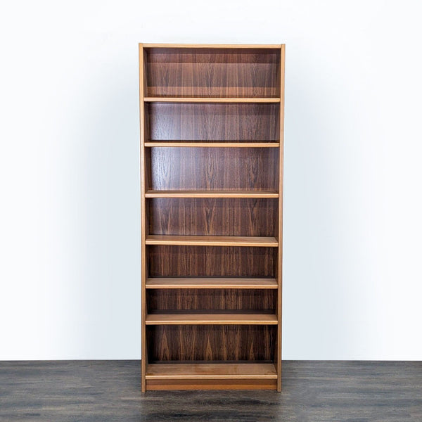 Front view of a tall, slim teak bookshelf by Scandinavian Designs with six open shelves for versatile storage.