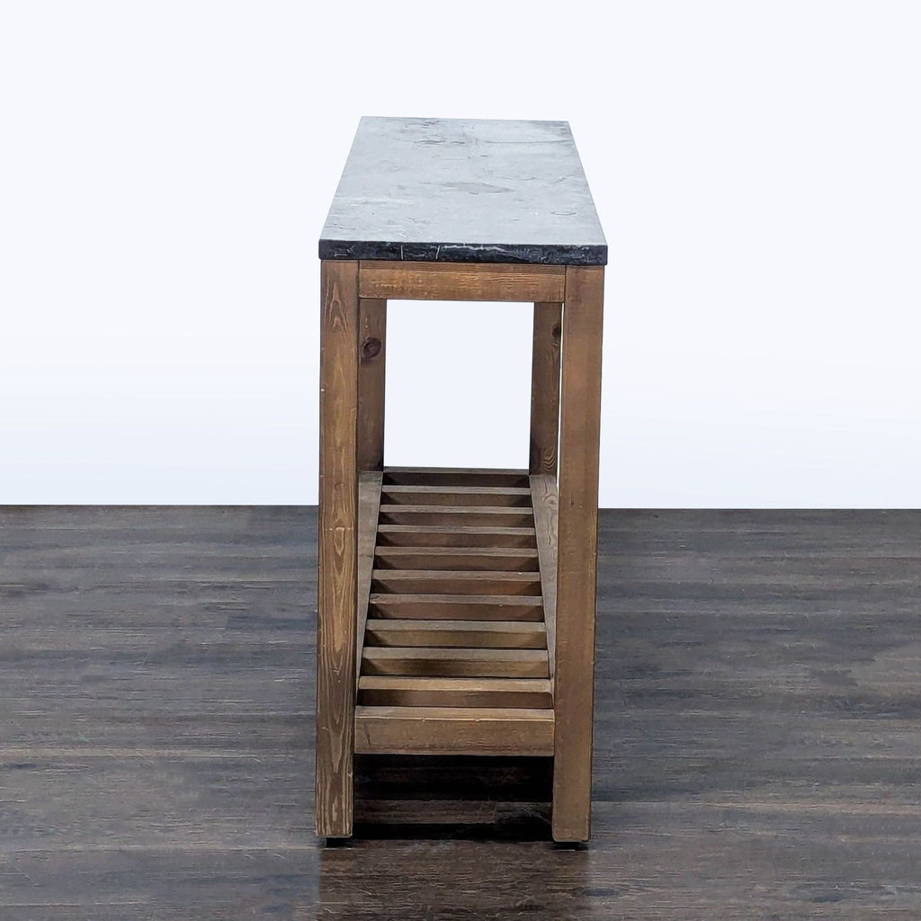 2. Narrow Pottery Barn console table viewed from the end, featuring a gray stone top and wooden slatted shelf below.