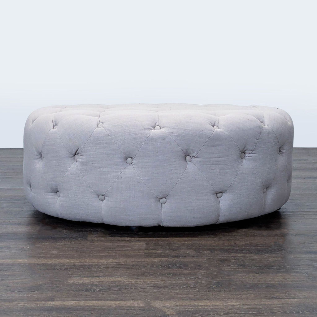 1. Round tufted ottoman with light gray fabric upholstery, placed on a dark wooden floor.