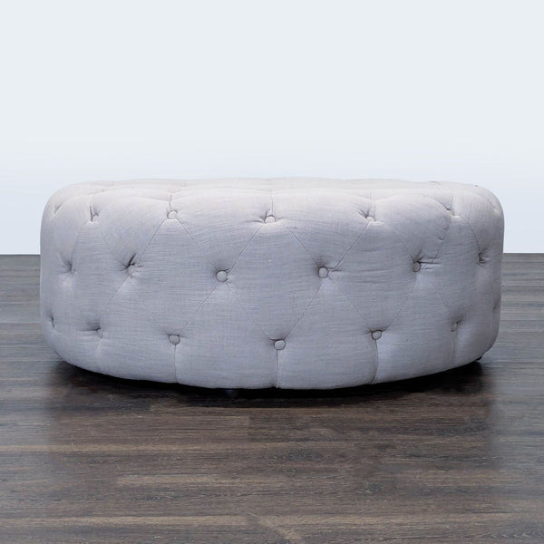 1. Round tufted ottoman with light gray fabric upholstery, placed on a dark wooden floor.