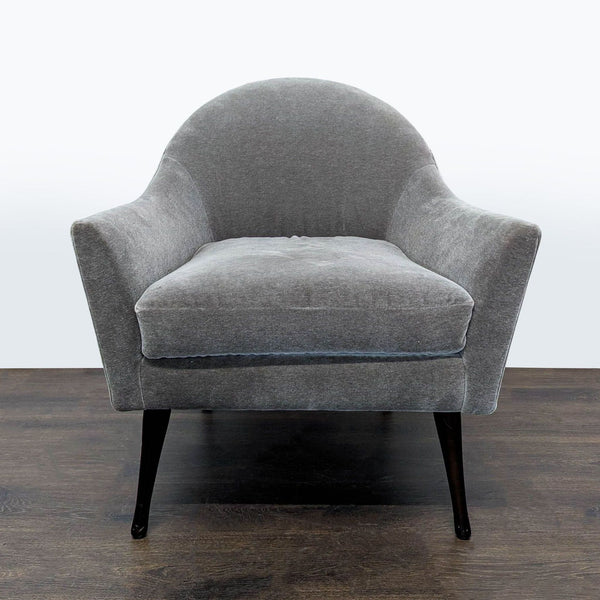 Gray velvet lounge chair with curved back and dark wood legs, offering modern, comfortable seating.  
