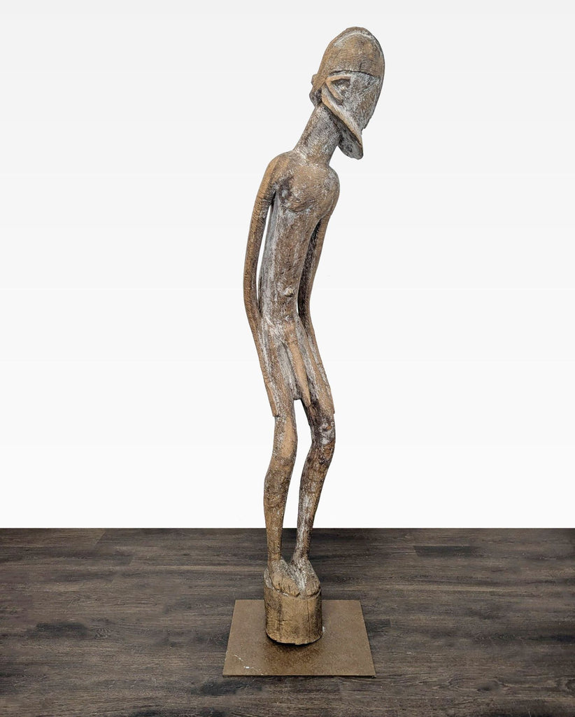Rustic hand-carved statue featuring elongated form and textured beard, stands on sturdy metal base.