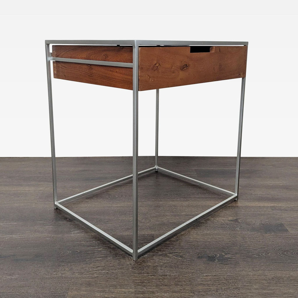 Modern CB2 nightstand combining a wood drawer and black metal frame, perfect for bedrooms.