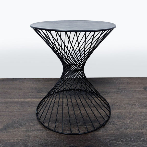 Modern accent table with hourglass wire frame, round top, and black metal finish, suitable for any room.  