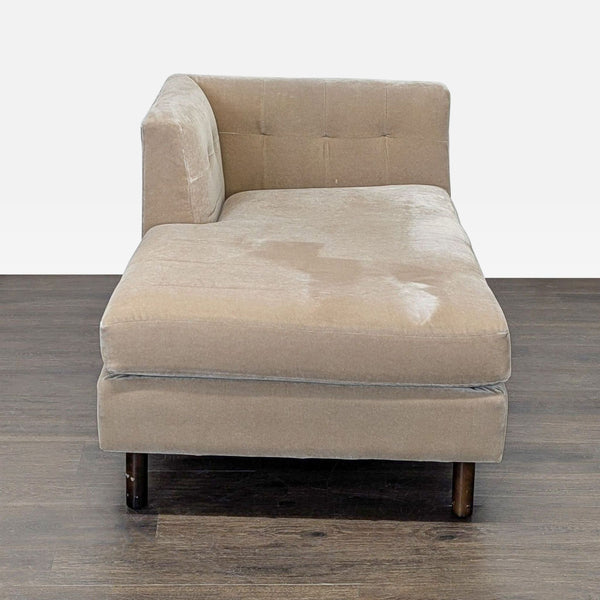 Beige chaise lounge with tufted backrest, soft cushion, and dark wood legs by Precedent.