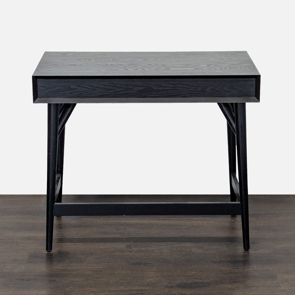 Sleek West Elm desk in black wood, offering a large surface and convenient storage drawer; ideal for versatile workspaces.