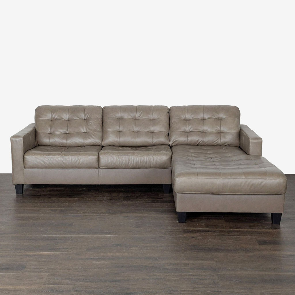 Taupe faux leather Ashley Furniture sectional with tufted details and spacious chaise, perfect for modern living rooms.