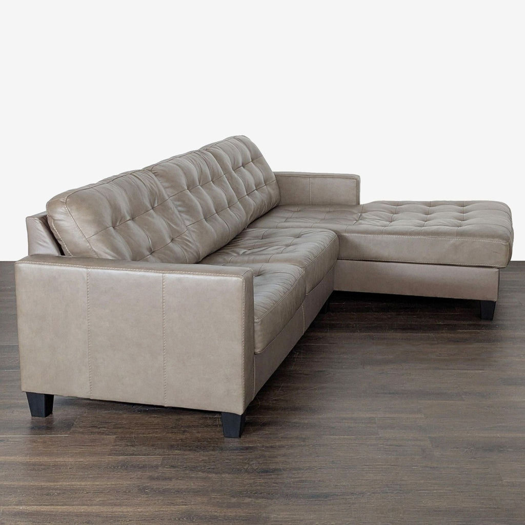 Modern Ashley Furniture sectional in taupe faux leather with tufted cushions and a cozy chaise for relaxing or entertaining.
