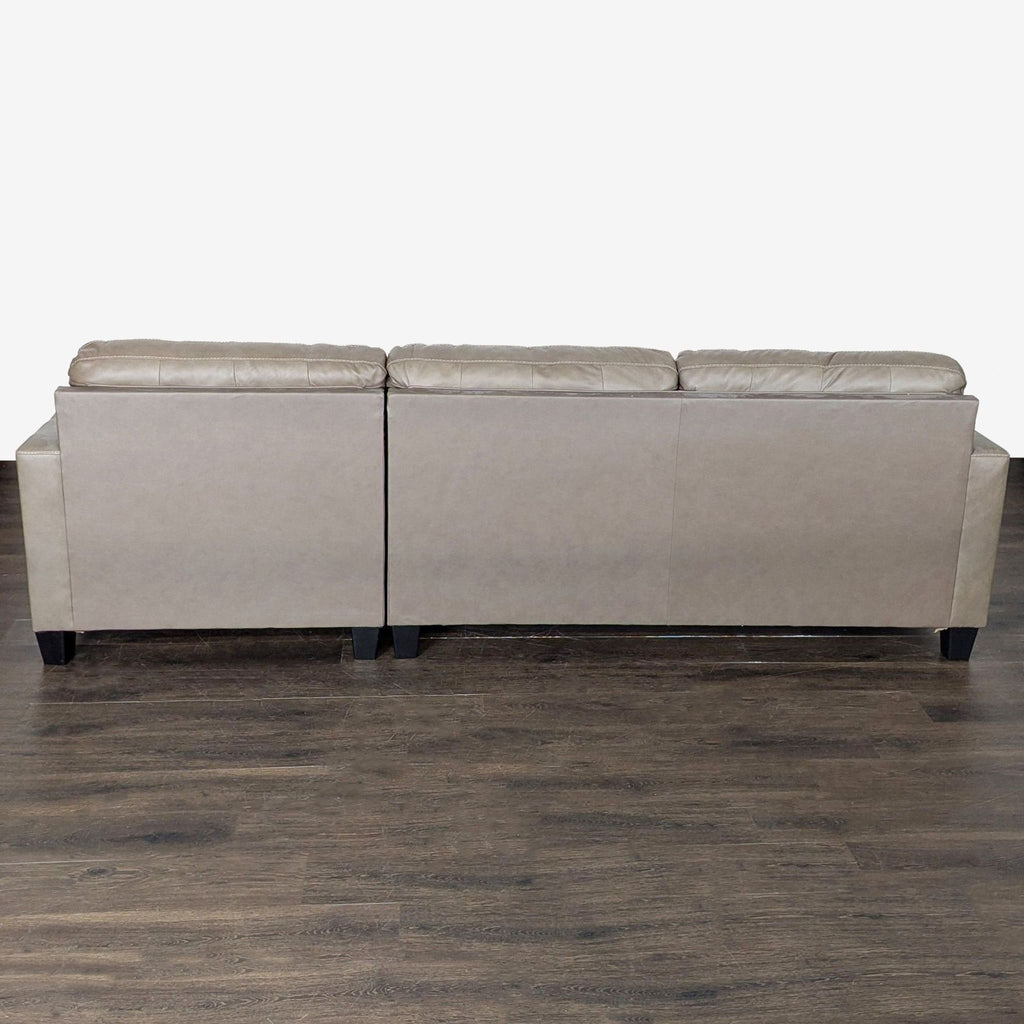 Ashley Furniture sectional sofa featuring a soft taupe finish, tufted upholstery, and a roomy chaise for extra comfort.