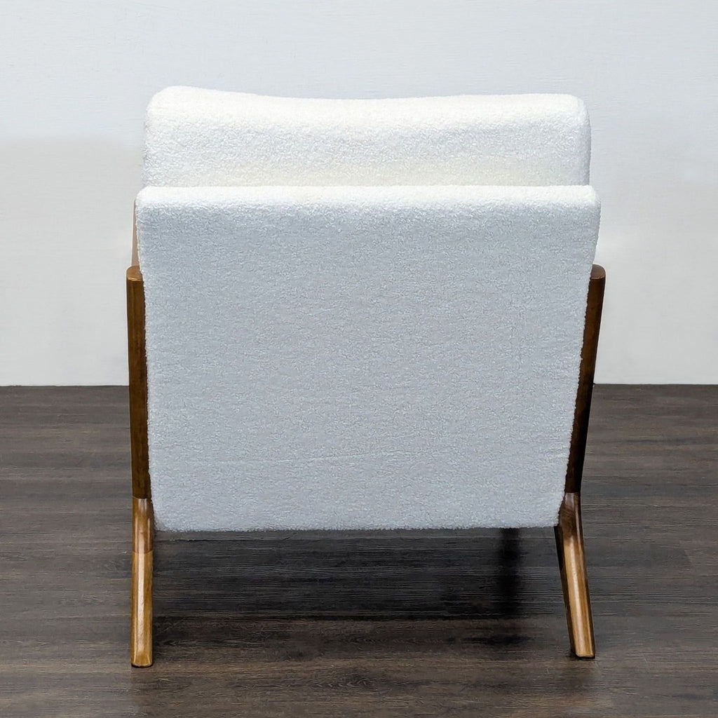 Plush lounge chair with minimalist wood frame and textured white cushions, blending comfort and timeless design.