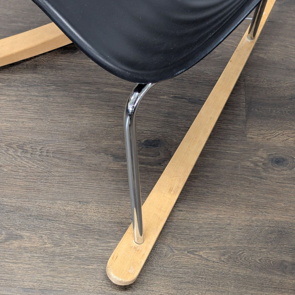 Sleek Vitra lounge chair with ergonomic black seat, metal frame, and wood rockers, ideal for relaxing.