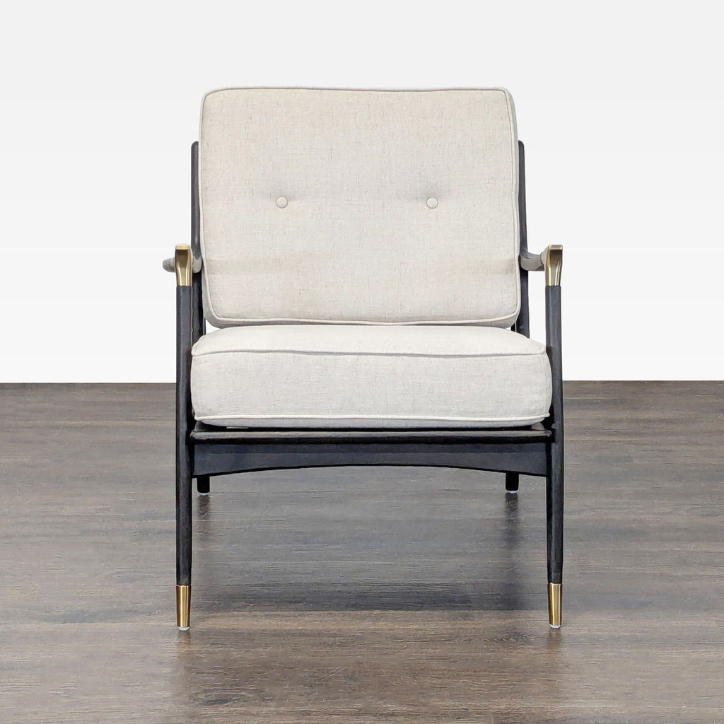 Modern lounge chair by Anthropologie with black wood frame, brass accents, and plush cream cushions.  