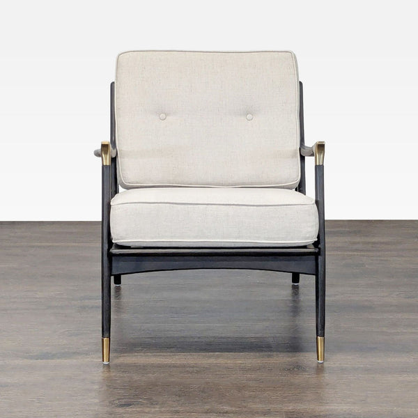 Modern lounge chair by Anthropologie with black wood frame, brass accents, and plush cream cushions.  