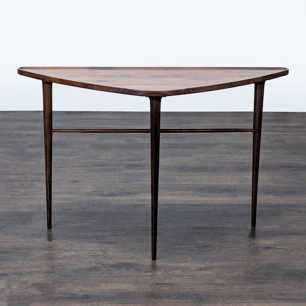 Triangular walnut side table with rounded edges, flat back, and slim tapered legs by Joybird.