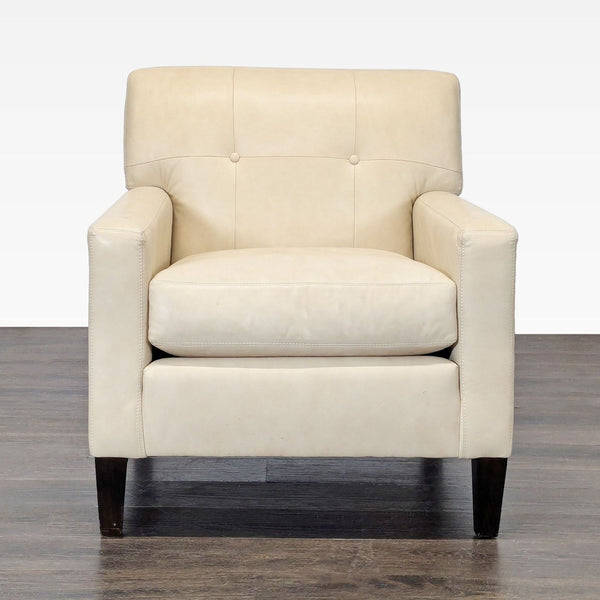 Cream leather lounge chair with dark wood legs, offering cushioned comfort and a modern design.