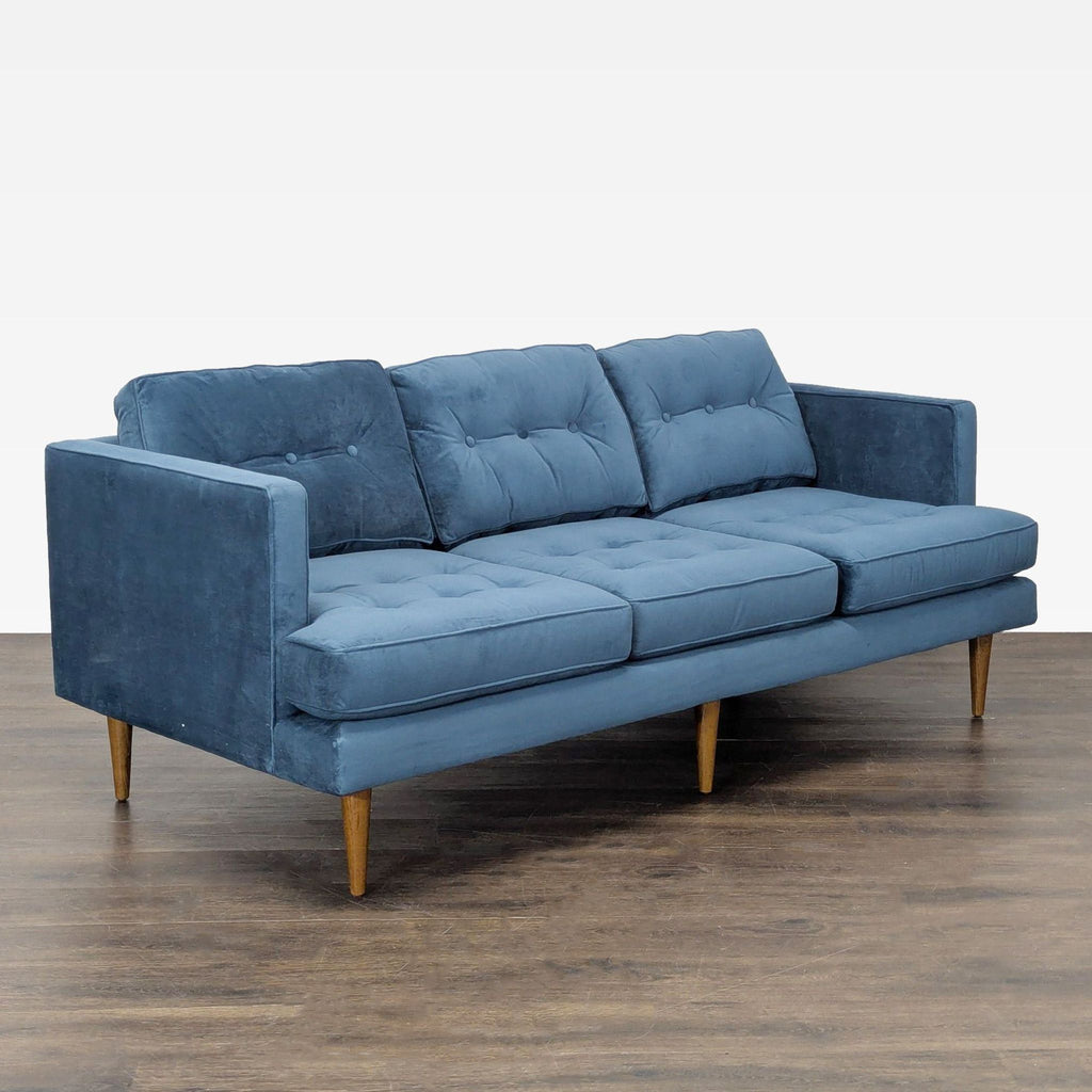 Contemporary 3-seat sofa with soft blue fabric, tufted design, and sturdy wood legs.