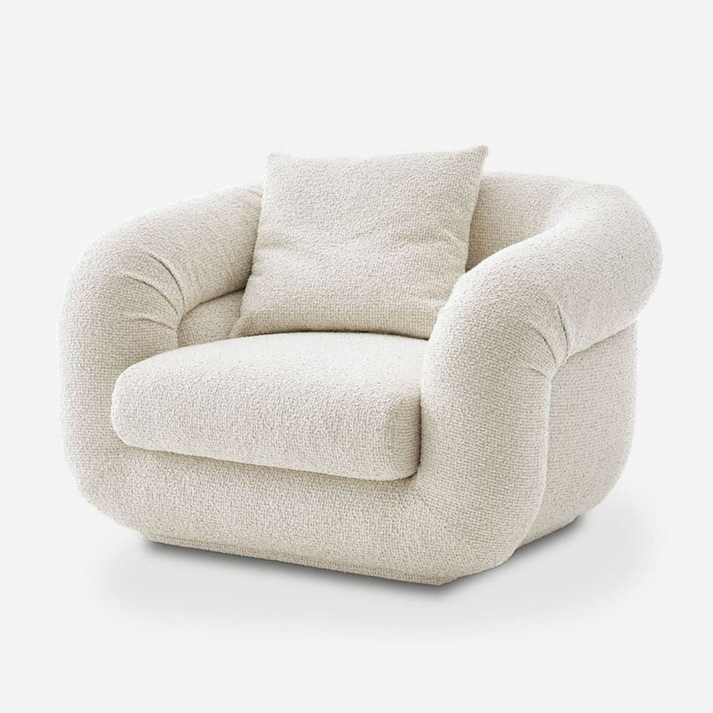 Modern Castlery armchair in soft cream bouclé, featuring a matching cushion and inviting, curved silhouette.