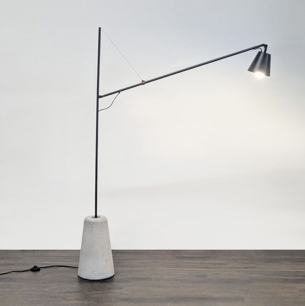 Modern EQ3 black metal floor lamp with concrete base and adjustable arm, showcased in a contemporary setting.
