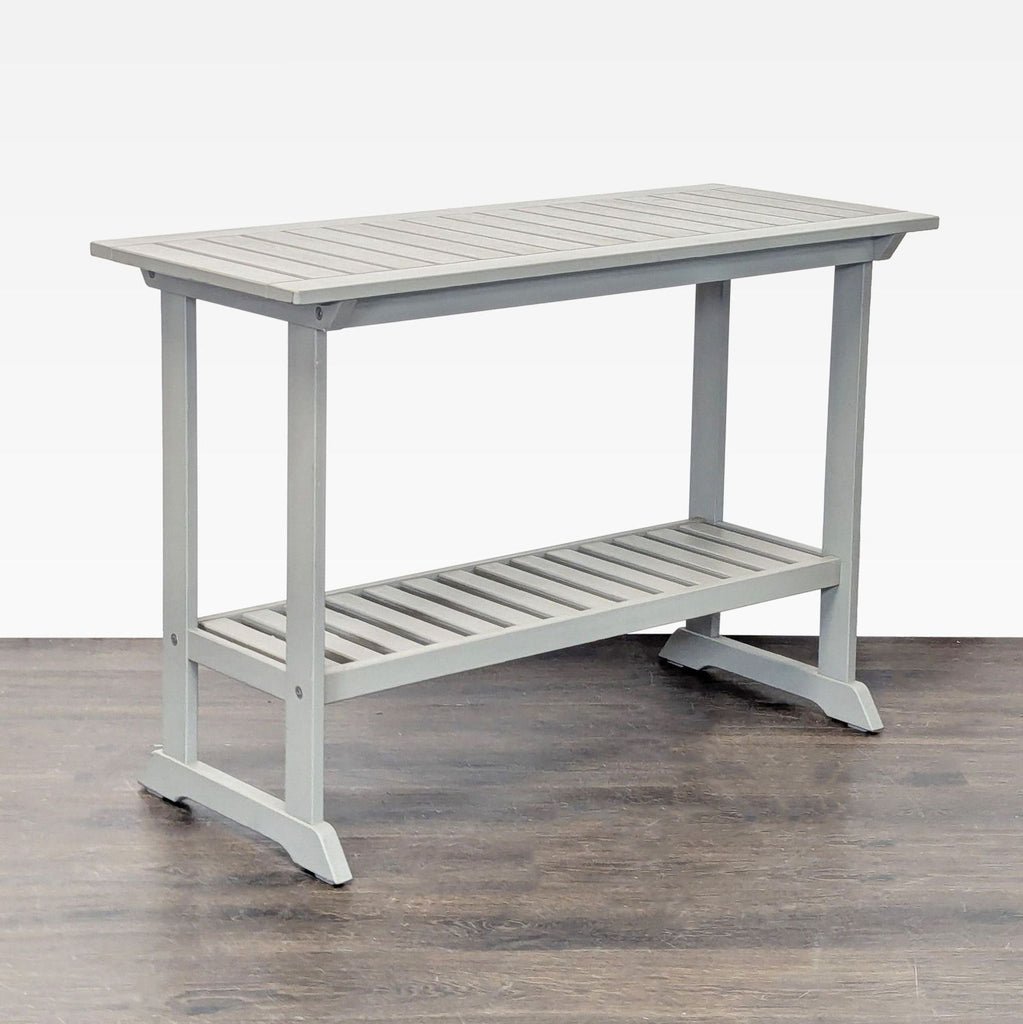 Gray wooden Ikea table featuring a slatted surface and an extra shelf, suitable for hallways or entryways.
