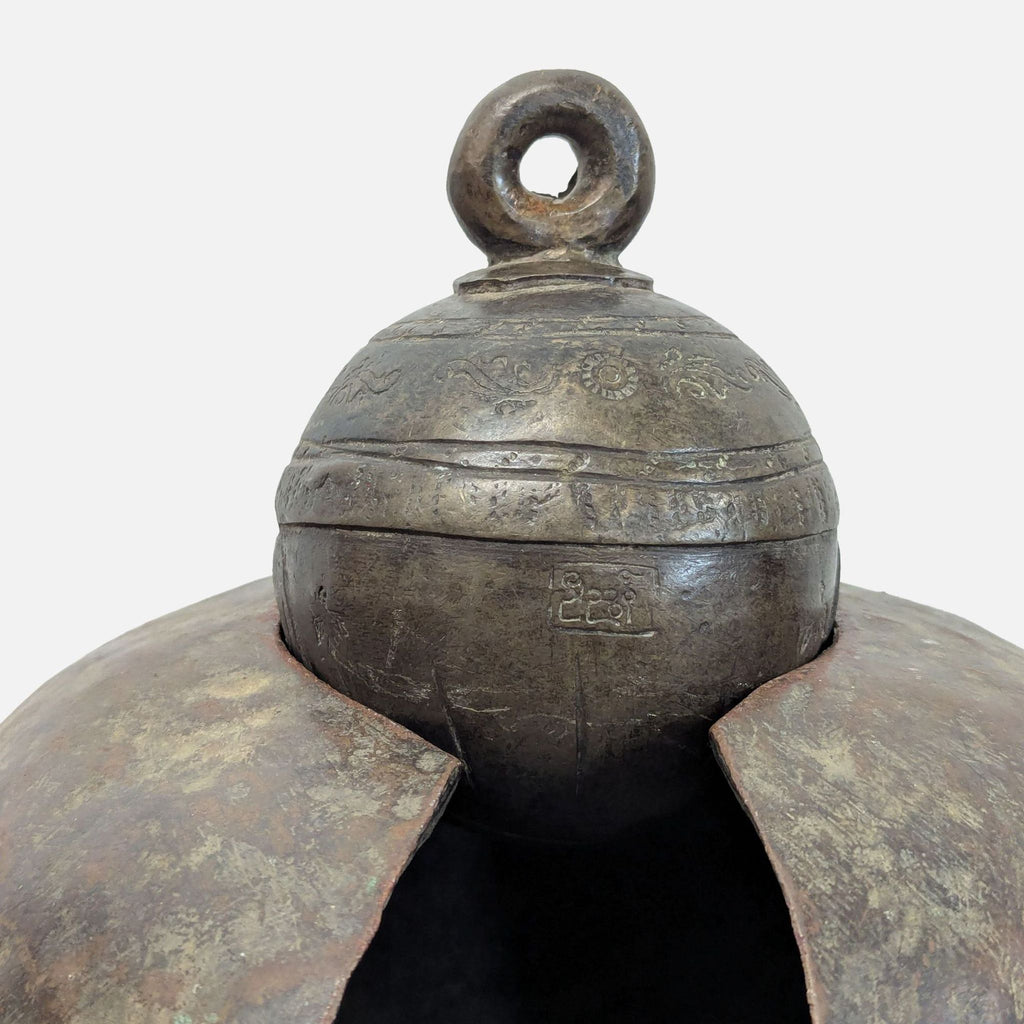 Decorative bronze livestock bell sculpture with rounded body, detailed collar, and a heavy hanging loop.