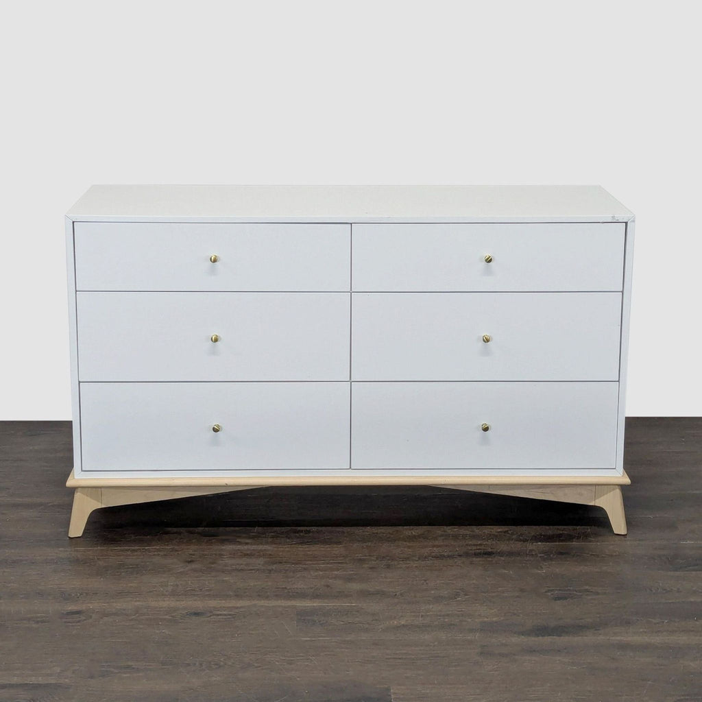 West Elm white dresser with six drawers, gold knobs, and a light wood base, blending modern style and function.  