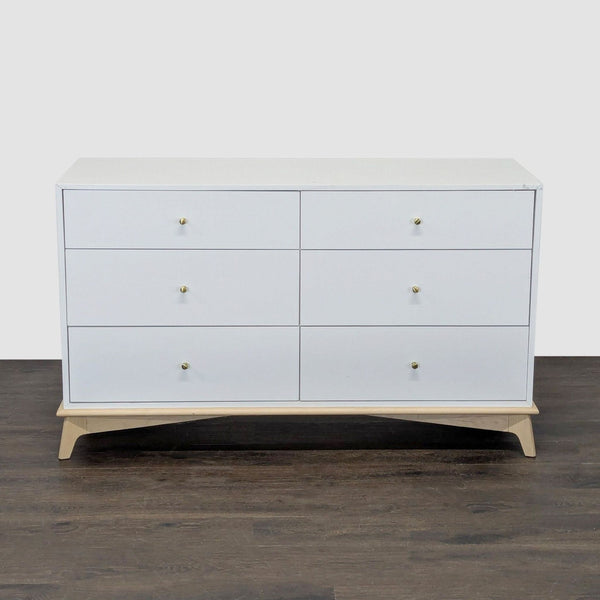 West Elm white dresser with six drawers, gold knobs, and a light wood base, blending modern style and function.  