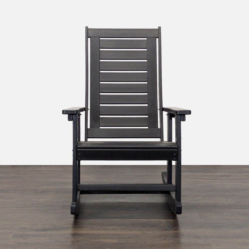 Black outdoor rocking chair with slatted back and seat, perfect for patios or porches, featuring armrests.