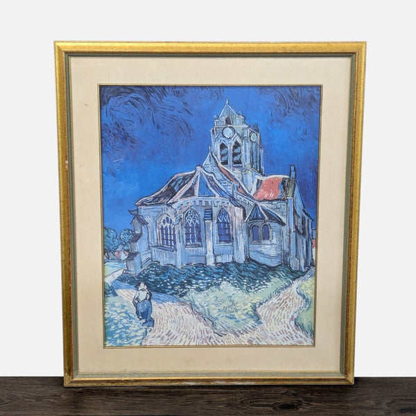 Framed Van Gogh print of "The Church at Auvers" in blue and earth tones, gold frame, minor wear visible.  
