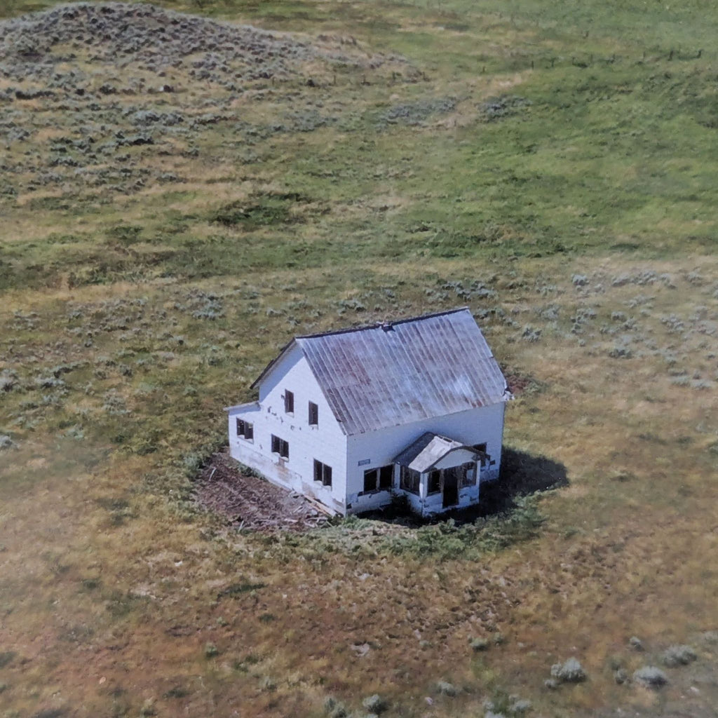 Framed artwork showing a bird’s eye view of a rustic farmhouse set in open grasslands, ready to hang.