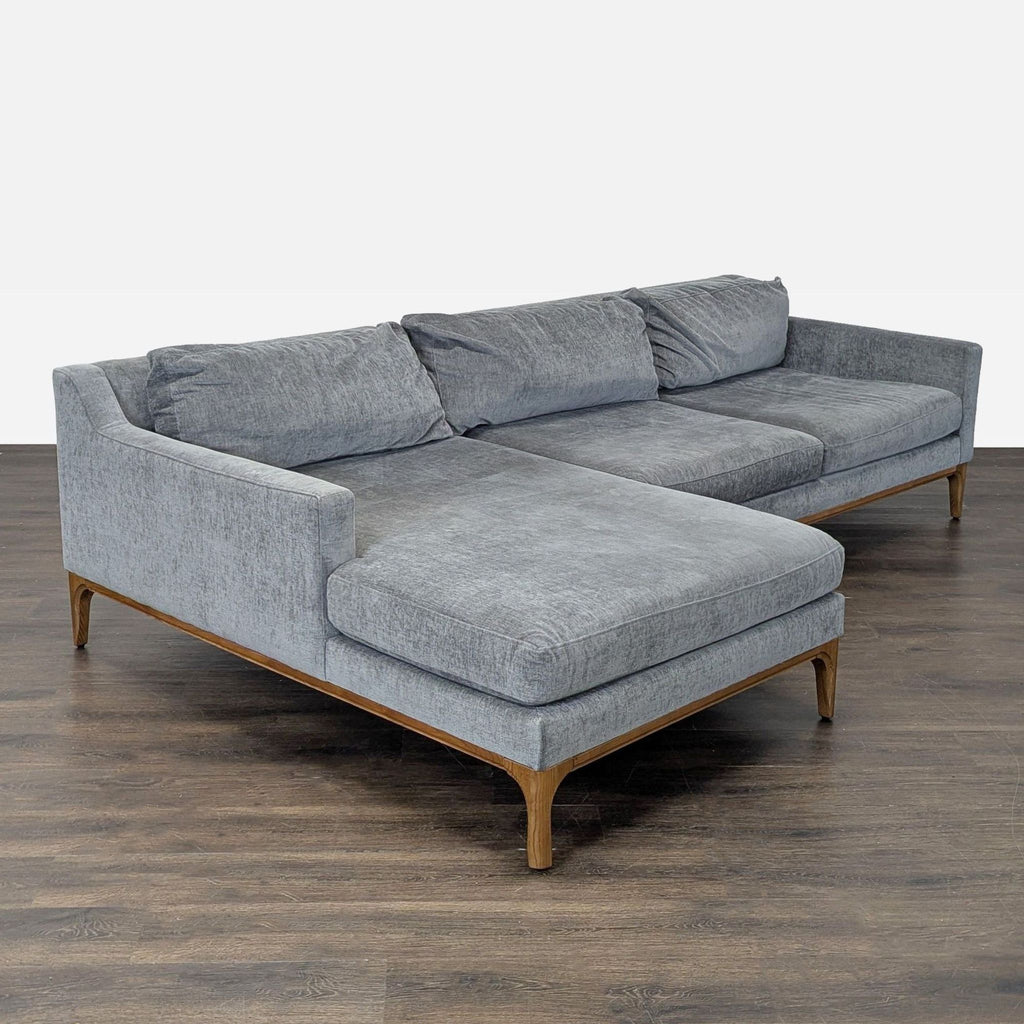 Modern West Elm gray sectional featuring a large chaise and sturdy wood base, perfect for family relaxation.