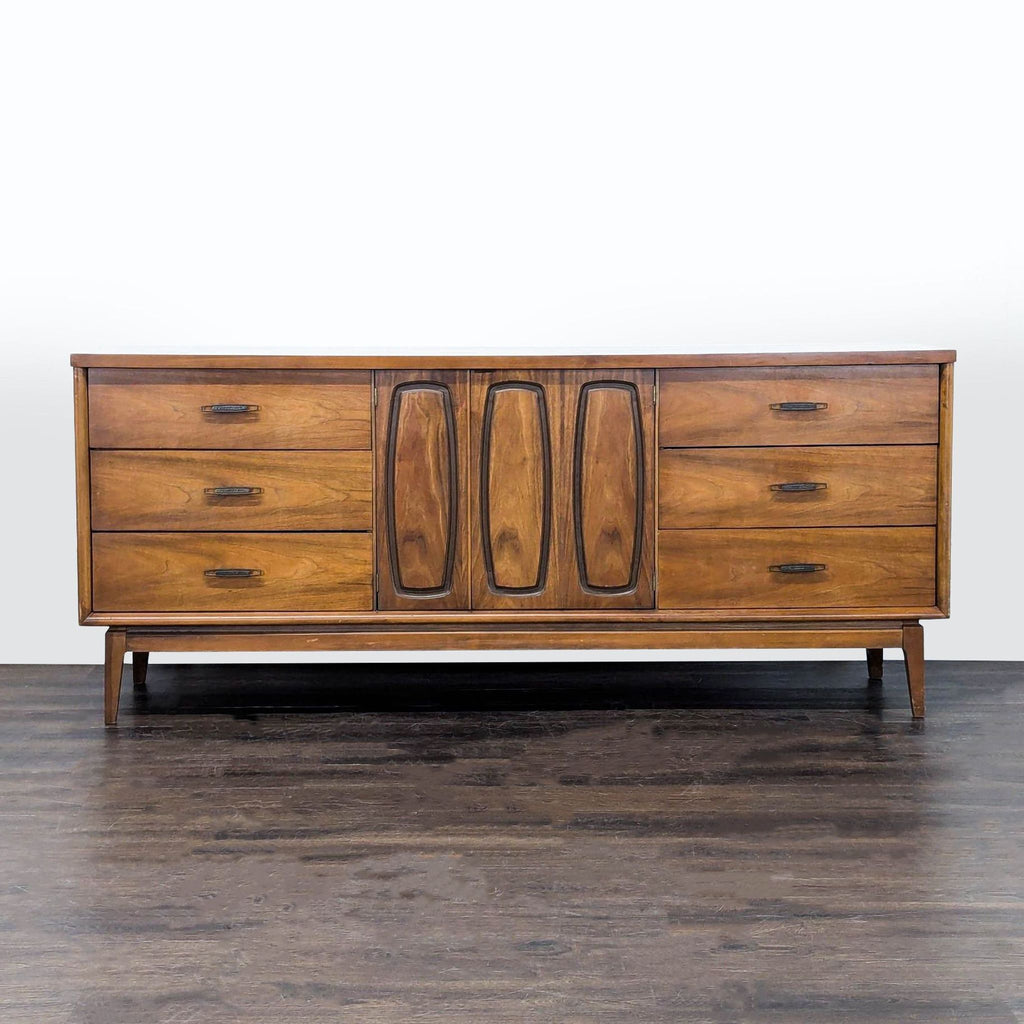 Mid-century walnut Broyhill credenza with six side drawers and central doors revealing three large drawers.
