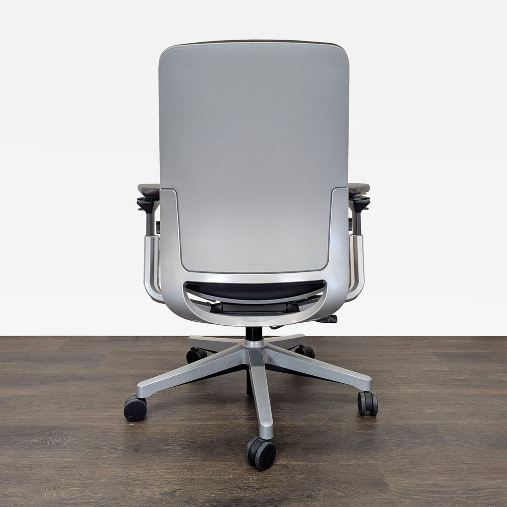 Ergonomic Steelcase chair with black padding, silver base, adjustable armrests, and wheels for office comfort.