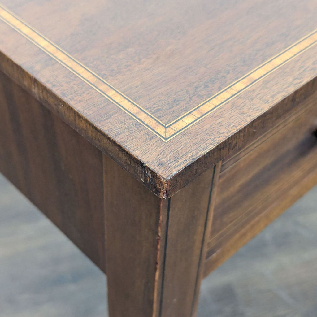 Late 18th-century neoclassical side table featuring inlaid details, three drawers, and tapered legs.