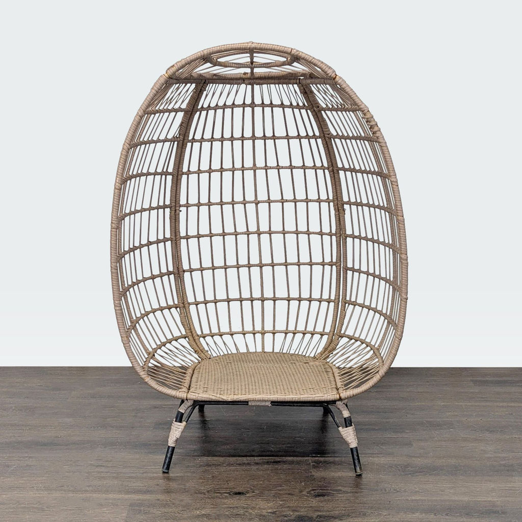 Egg-shaped rattan chair with metal legs, open weave design, suitable for indoor or outdoor relaxation.