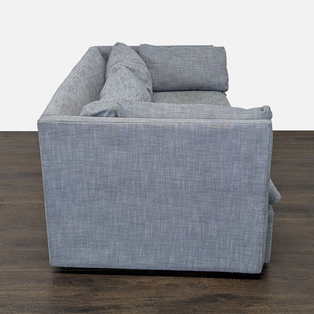 Contemporary West Elm gray sofa fits three, boasting plush cushions and sleek design for living rooms or offices.