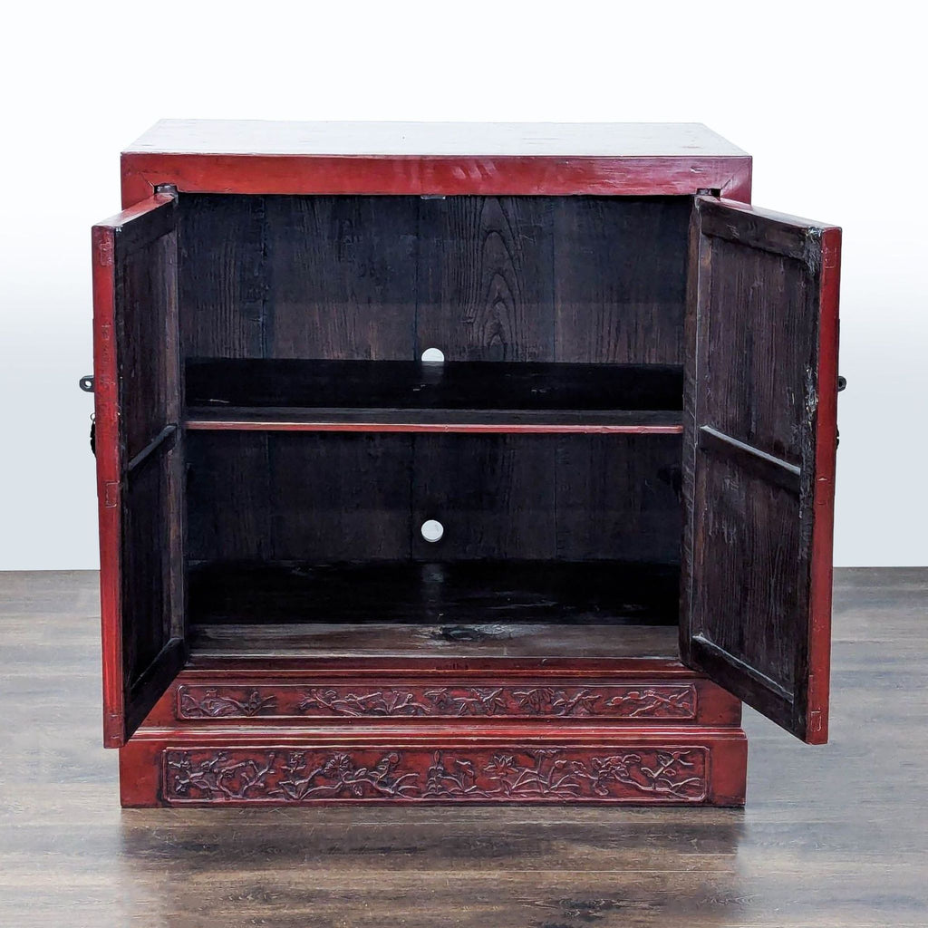 Elegant red lacquer cabinet featuring a detailed carved base and a decorative engraved metal lock plate.  