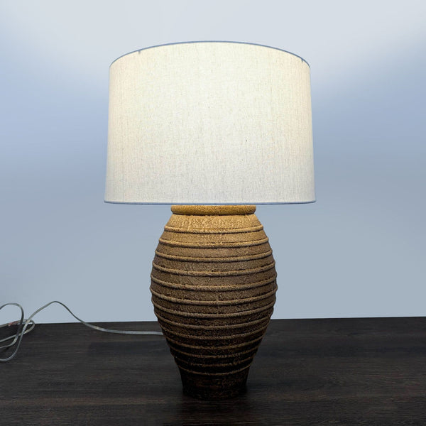 Textured brown ceramic table lamp with a white lampshade, suitable for various room styles.