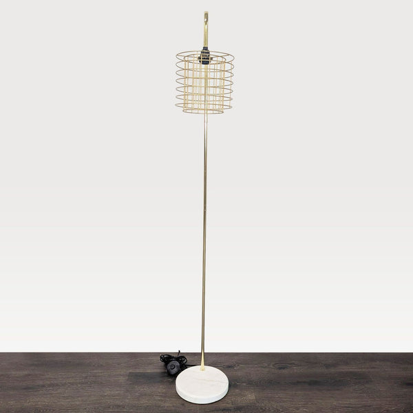 Modern gold floor lamp with wire cage shade and marble base, ideal for stylish living or office spaces.